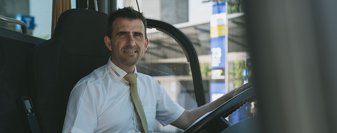 Porträt eines Busfahrers von VBL REISEN am Lenkrad eines Reisecars.